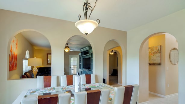 A dining area with a table set for six, surrounded by arched doorways leading to other rooms. - Games, Bikes & Kids Play Area: Ocala Family Home (Ocala)