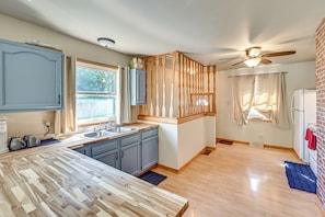 A modern kitchen with a wooden countertop, blue cabinets, and a ceiling fan. - 4 Mi to Lake Michigan: Updated Benton Harbor Home! (Benton Harbor)
