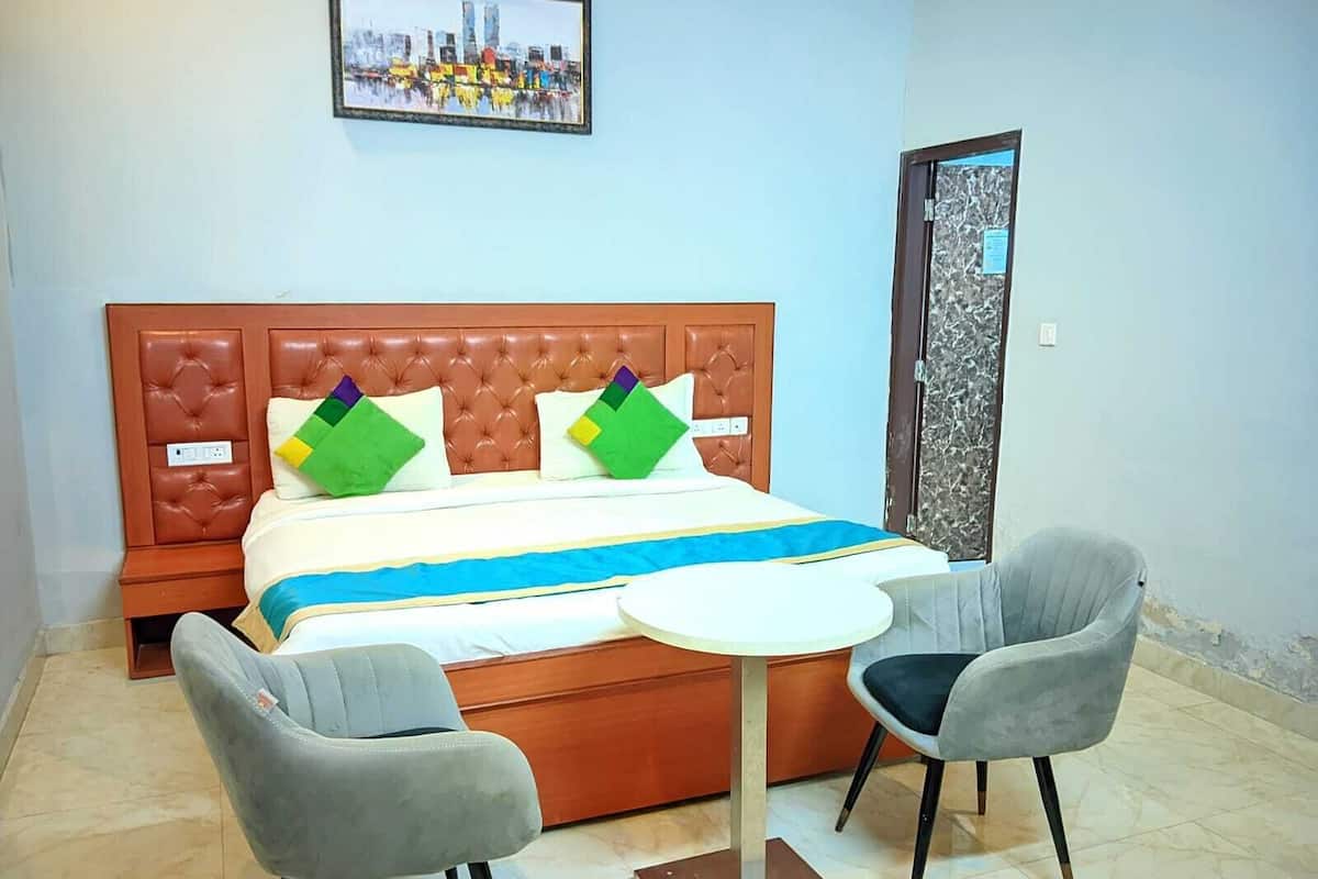 A hotel room with a bed, two armchairs, a small table, and a framed picture on the wall.