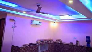 A modern reception area with a marble counter, ceiling fan, and air conditioning unit. - Hotel Expo Mart Inn Behind India Expo (Greater Noida)