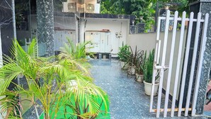 A courtyard with potted plants, a gate, and a building with electrical panels. - Hotel Expo Mart Inn Behind India Expo (Greater Noida)