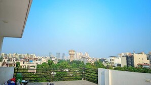 A balcony with a cityscape view, including a water tower and various buildings. - Hotel Expo Mart Inn Behind India Expo (Greater Noida)