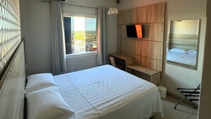Ett hotellrum med en säng, ett skrivbord, en tv och ett fönster med utsikt.