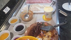 En buffédisk med ett varierat utbud av mat, inklusive skivad frukt, kött och desserter.
