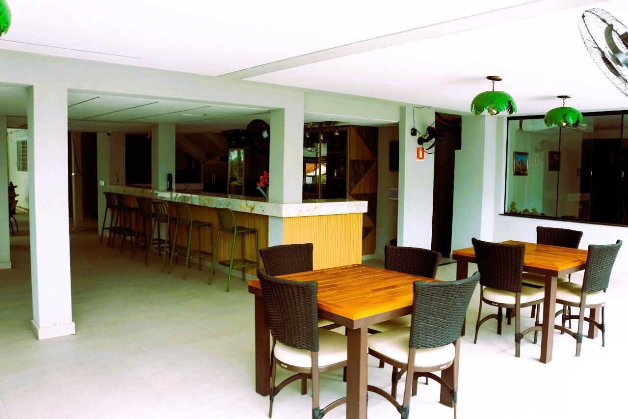 Un comedor con mesa y sillas de madera, una barra con taburetes y un ventanal con vistas.