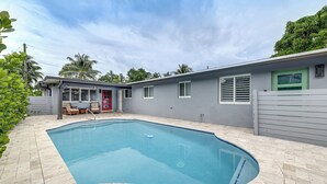 A swimming pool with a curved edge, surrounded by a tiled deck. - Walkable Island City Oasis w/ Private Heated Pool! (Wilton Manors)