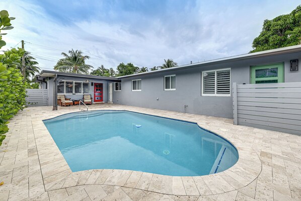 A swimming pool with a curved edge, surrounded by a tiled patio. - Walkable Island City Oasis w/ Private Heated Pool! (Wilton Manors)