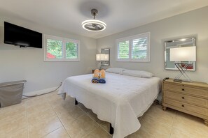 A bedroom with a bed, a dresser, a TV mounted on the wall, and windows with blinds. - Walkable Island City Oasis w/ Private Heated Pool! (Wilton Manors)