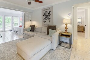 A spacious living room with a large sectional sofa, a small side table, and a wall-mounted artwork titled "LE JARDIN BOTANIQUE". - Walkable Island City Oasis w/ Private Heated Pool! (Wilton Manors)