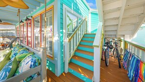 A covered deck with a wooden staircase, a seating area with cushions, and bicycles parked on the right. - Steps to Ocean! PCB Family Home w/ Outdoor Oasis (Panama City Beach)