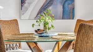 A dining table with a glass top, surrounded by woven chairs, a vase with a plant, and a bowl. - Steps to Ocean! PCB Family Home w/ Outdoor Oasis (Panama City Beach)