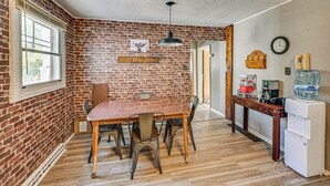 Una cucina con parete in mattoni, tavolo e sedie di legno.