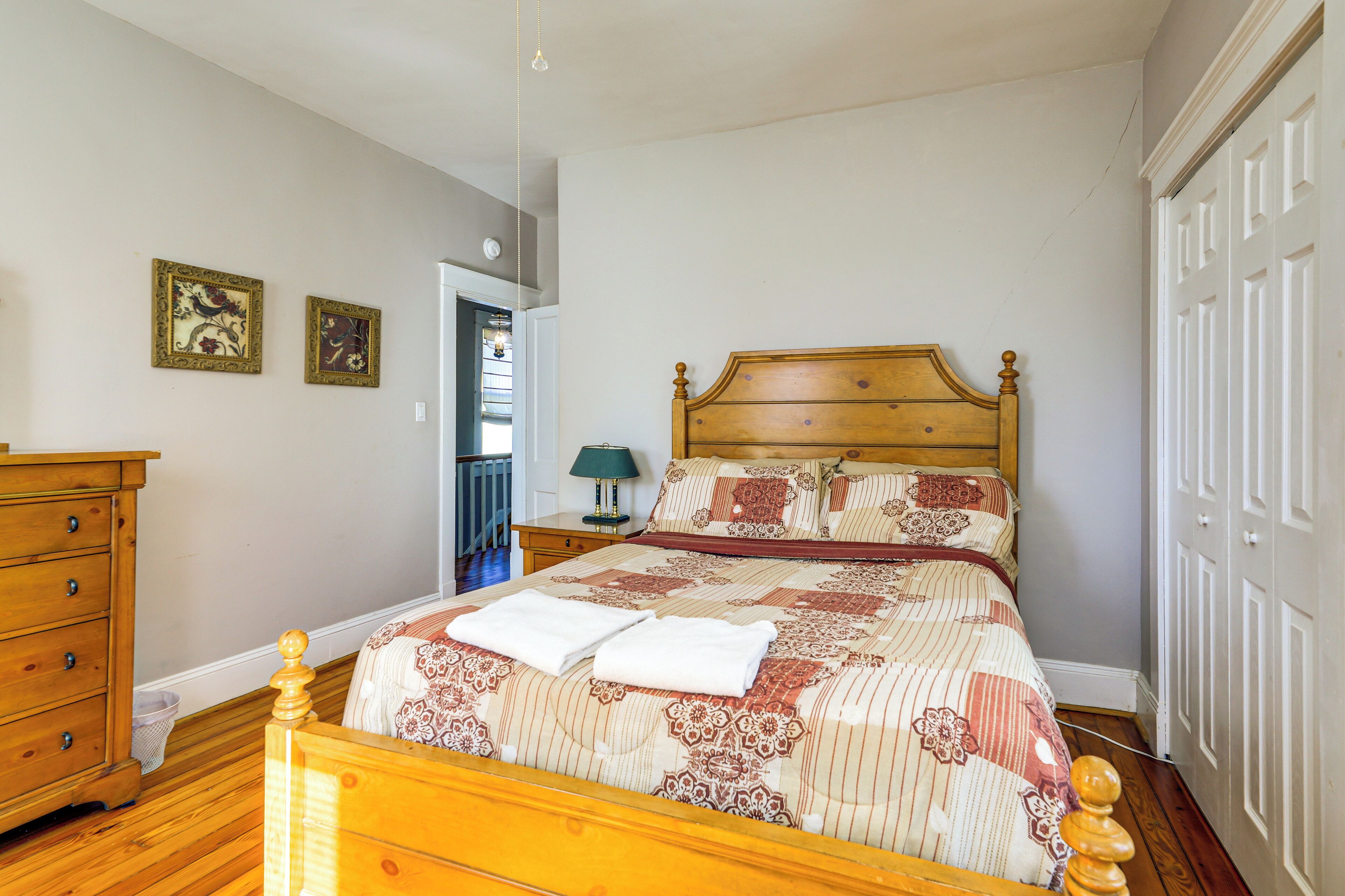 A bedroom with a wooden bed, a dresser, and two framed pictures on the wall.