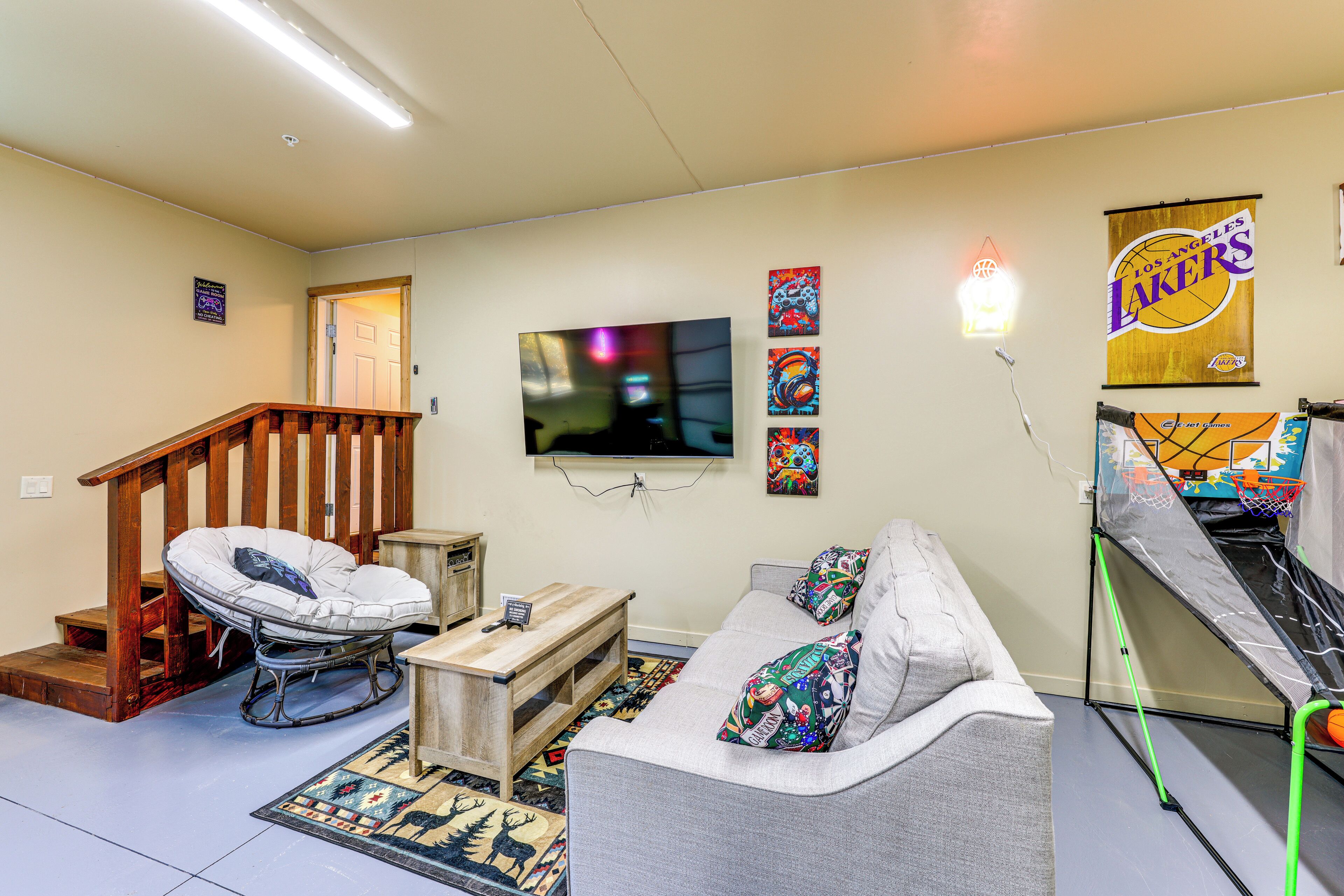 A living room with a TV, a couch, a chair, a small table, and a basketball hoop.