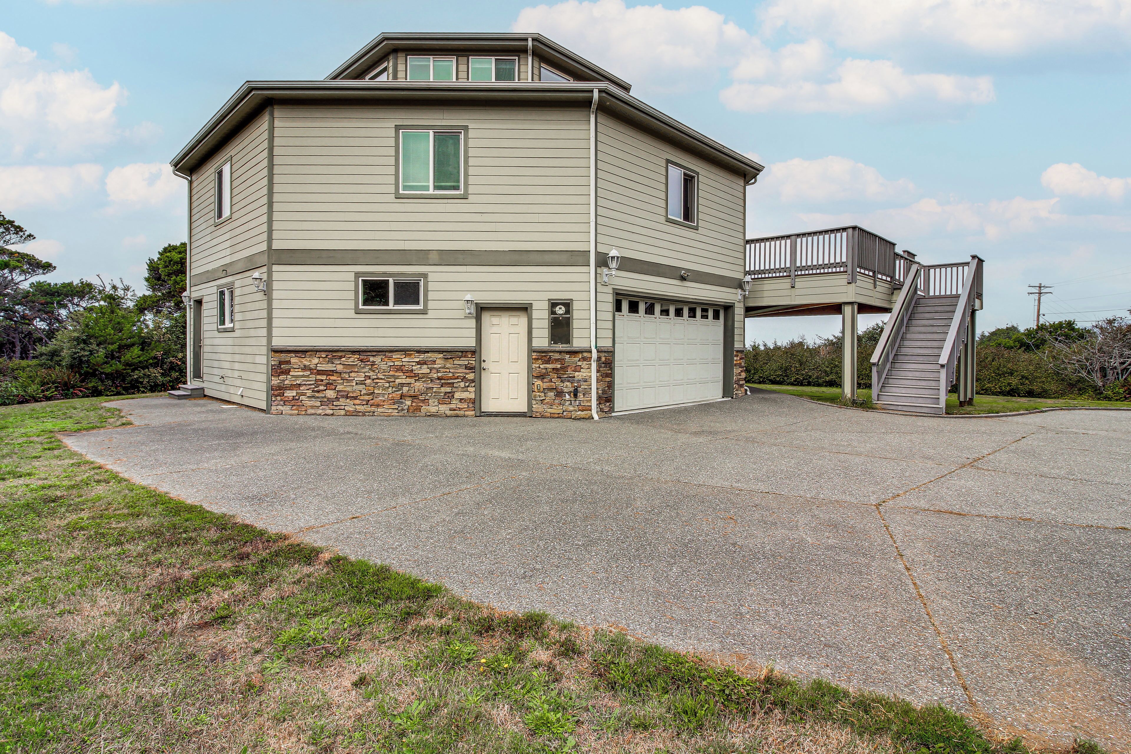 A two-story house with a stone foundation, a garage, and a covered outdoor staircase.