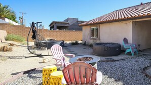 Un patio con mobiliario exterior, un brasero y un edificio con tejado de baldosas.
