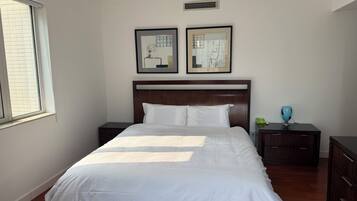 A neatly made bed with white linens, a wooden headboard, and two bedside tables with lamps.