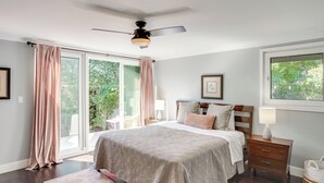 A bedroom with a bed, a nightstand, a ceiling fan, and a window with curtains.