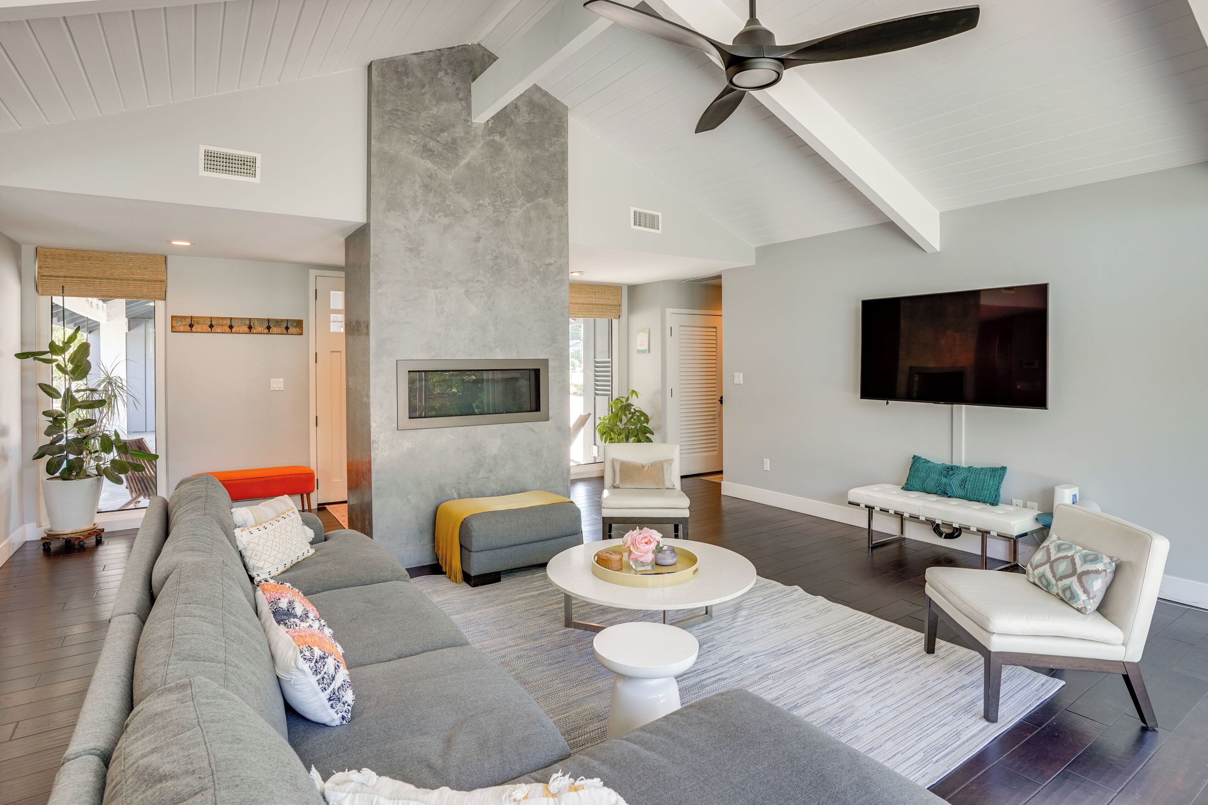 A modern living room with a sectional sofa, a round coffee table, and a white armchair.