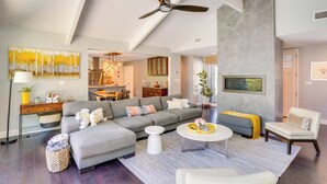 A spacious living room with a large sectional sofa, a coffee table, and a dining area in the background.