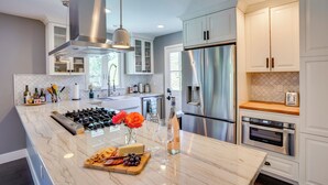 A modern kitchen with stainless steel appliances, marble countertops, and white cabinetry.