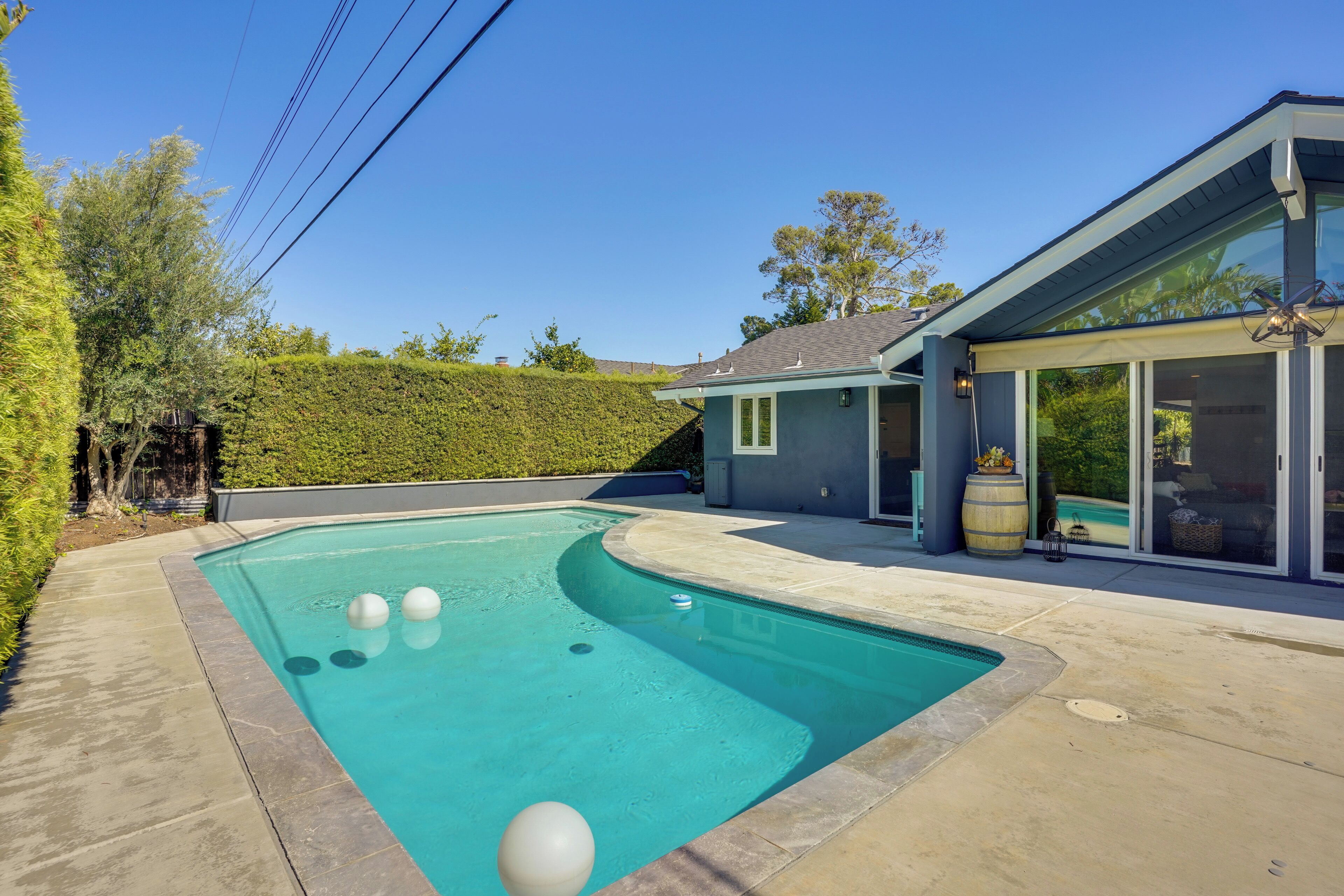 Une piscine à bord incurvé, un patio couvert et une vue sur un paysage vallonné.
