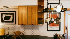 A kitchen with wooden cabinets, a hanging pot rack, and a brick backsplash. - The Magic Teacup:  Steps from the Slopes and Trails! (Davis)
