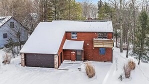 A two-story house with a garage, surrounded by snow-covered ground and trees. - The Magic Teacup:  Steps from the Slopes and Trails! (Davis)
