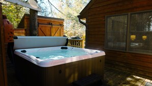 A hot tub on a wooden deck with a view of trees and a wooden cabin. - The Magic Teacup:  Steps from the Slopes and Trails! (Davis)
