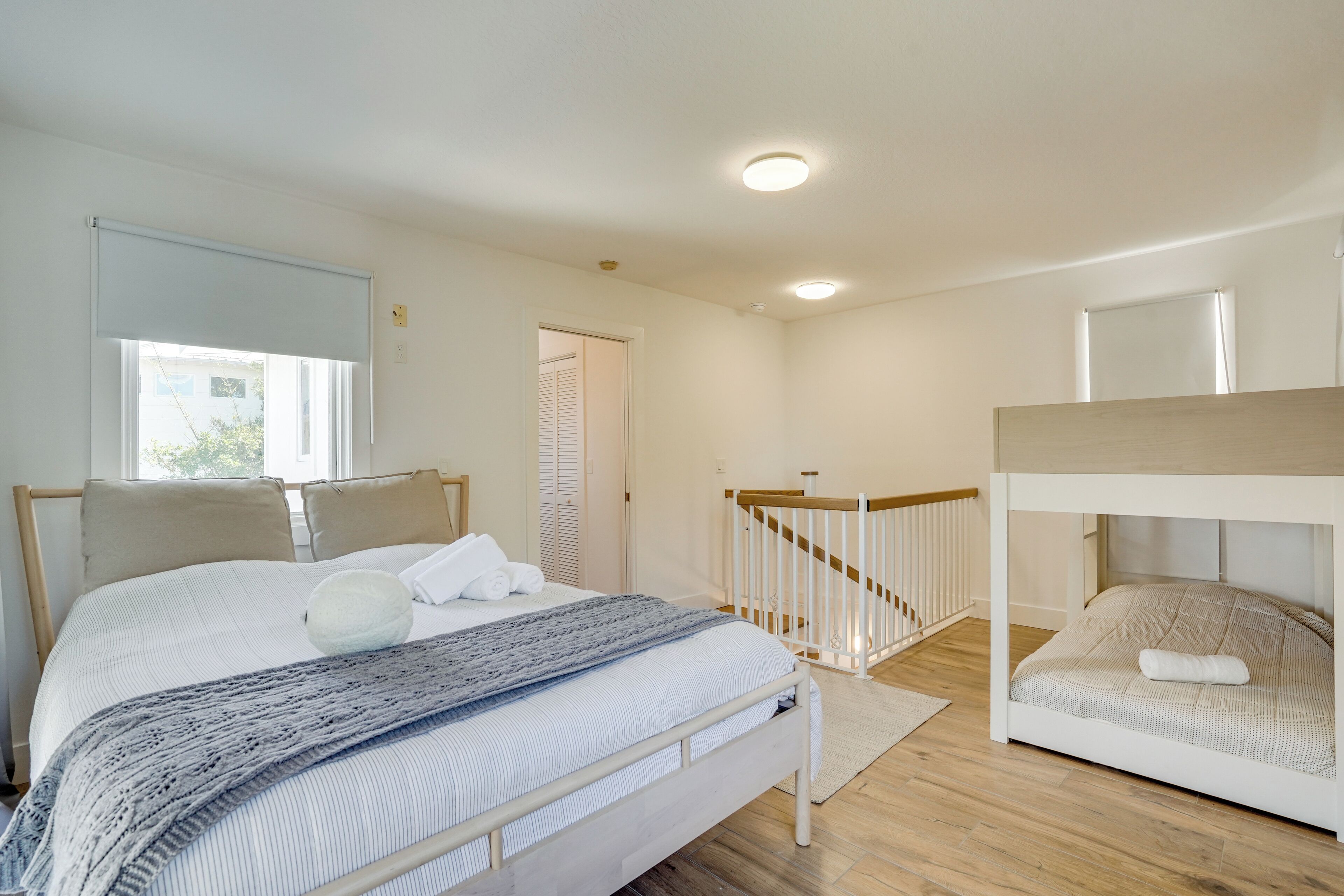 Ein Schlafzimmer mit einem Bett, einem Etagenbett, einem Fenster mit Jalousien, einer Tür und einer Deckenleuchte.