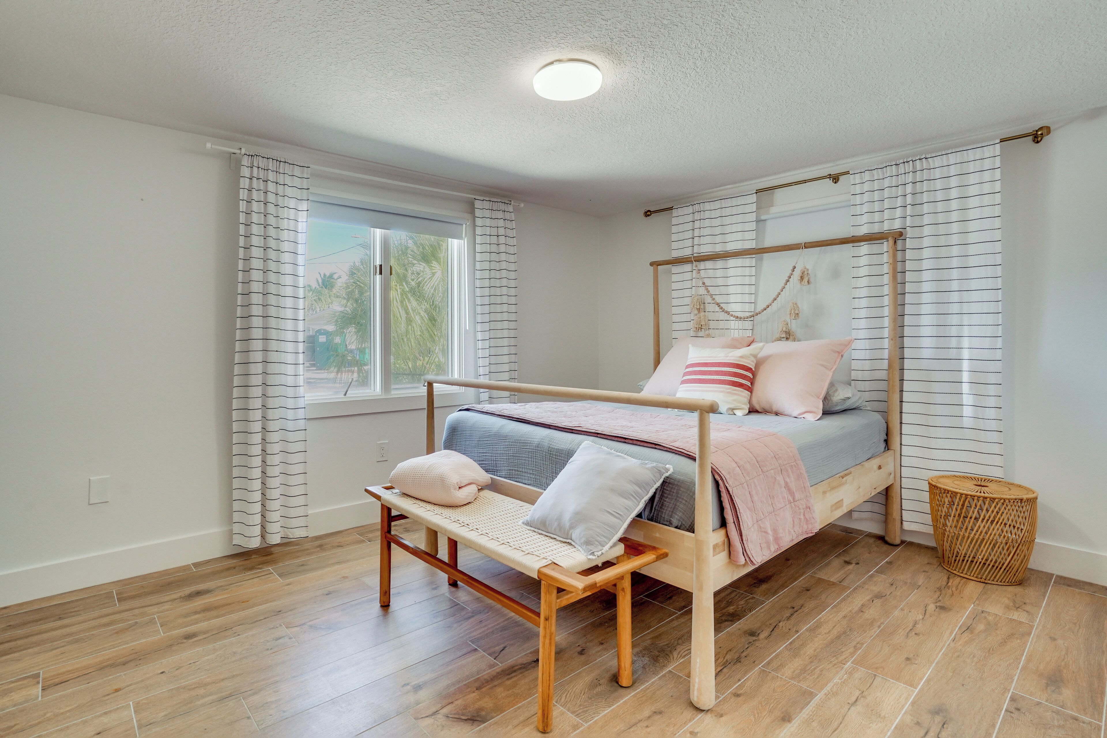 Une chambre à coucher avec un lit en bois, un banc et une fenêtre avec des rideaux.
