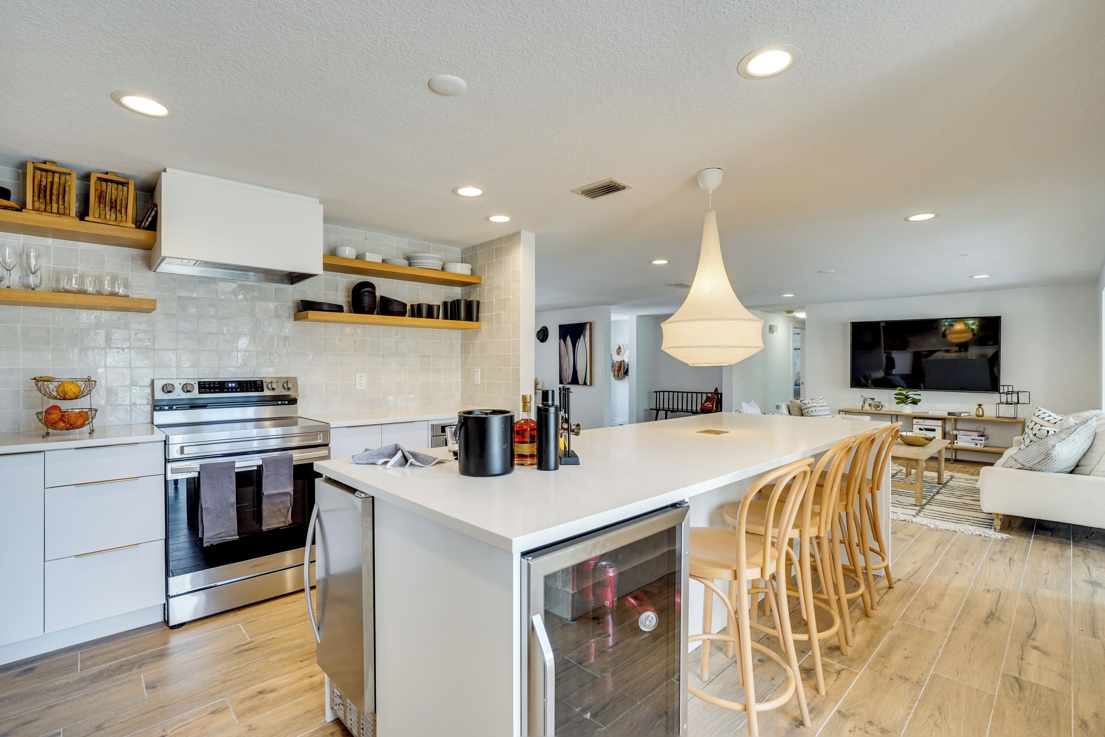 A modern kitchen with a central island, built-in oven, and wooden shelves.