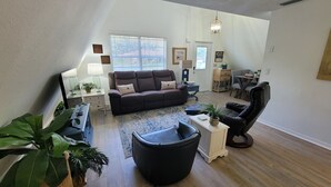 En stue med sofa, lænestol, sofabord og plantekasser.