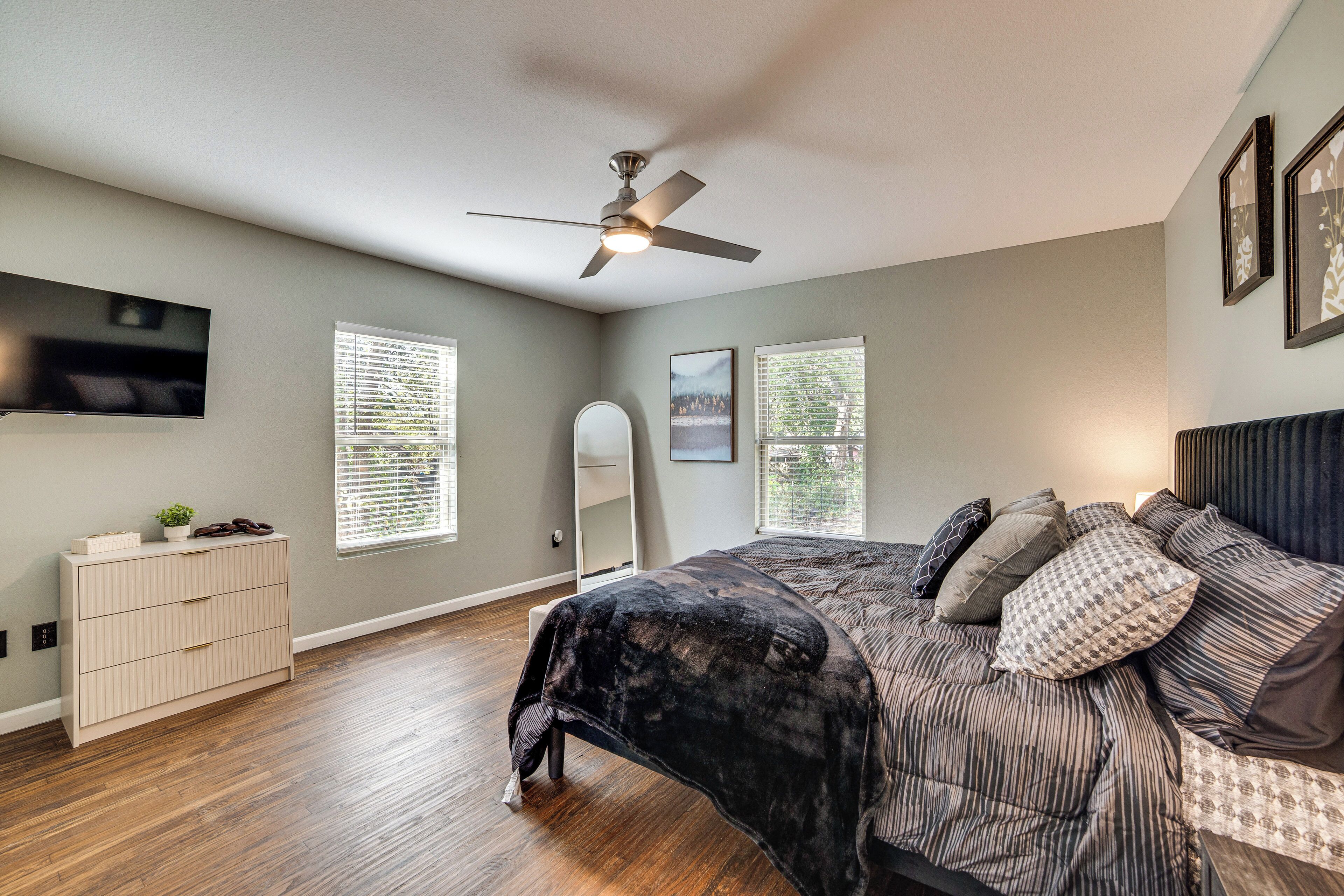 A bedroom with a bed, a ceiling fan, a TV, and a dresser.