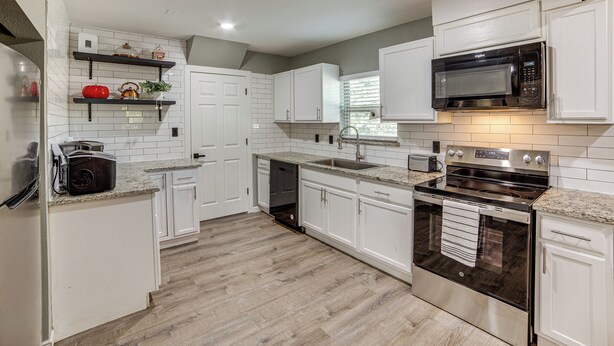 A modern kitchen with white cabinetry, a stainless steel stove, a microwave, and a built-in oven. - Walk to East Texas A&m! Home w/ Pet-friendly Yard (Commerce)