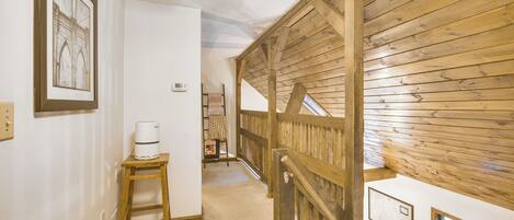 A hallway with a wooden staircase, a white wall with a framed picture, and a small table with a white device.