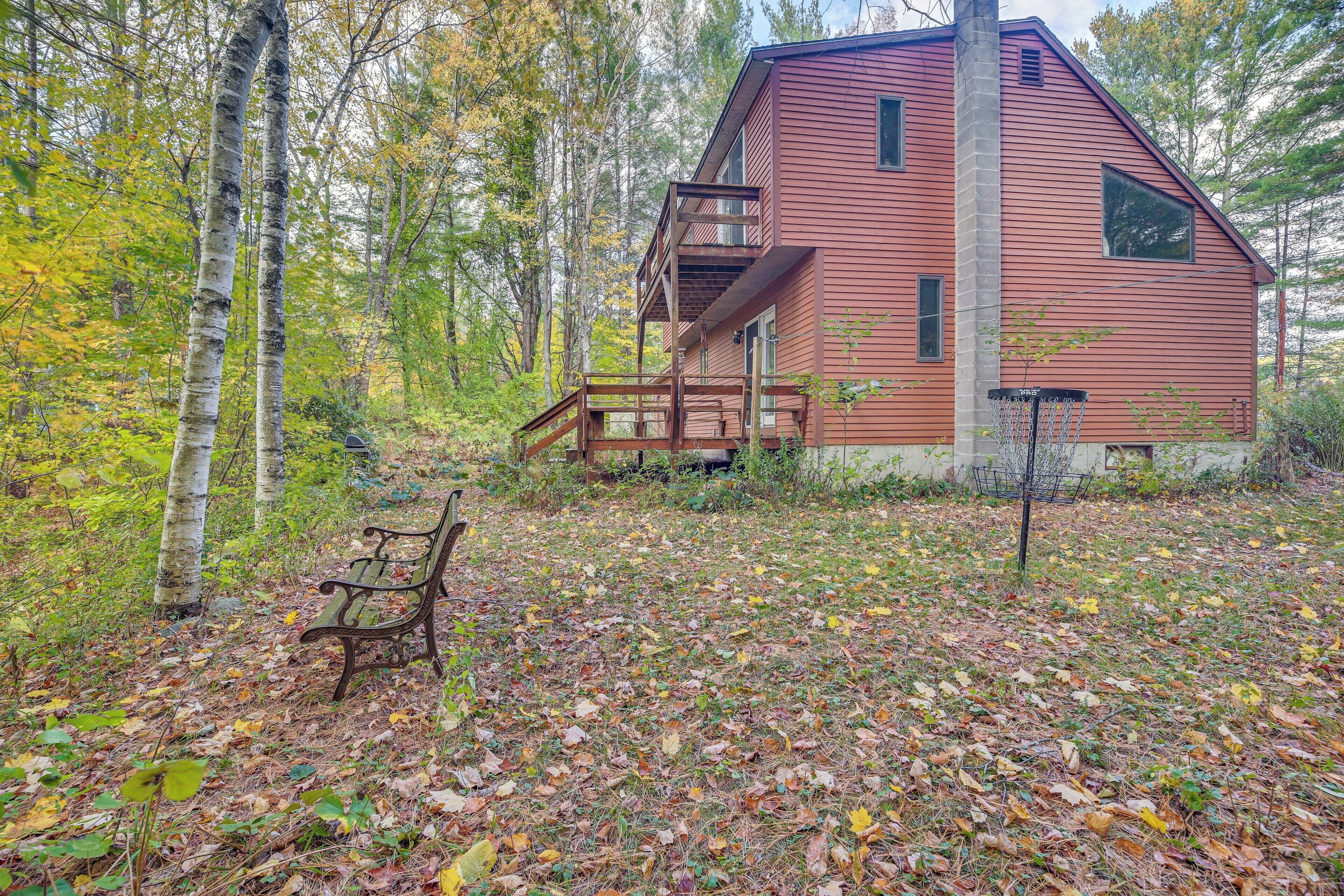 Une cabane rustique dotée d’une terrasse en bois et d’une seule pièce, située au cœur d’une forêt.