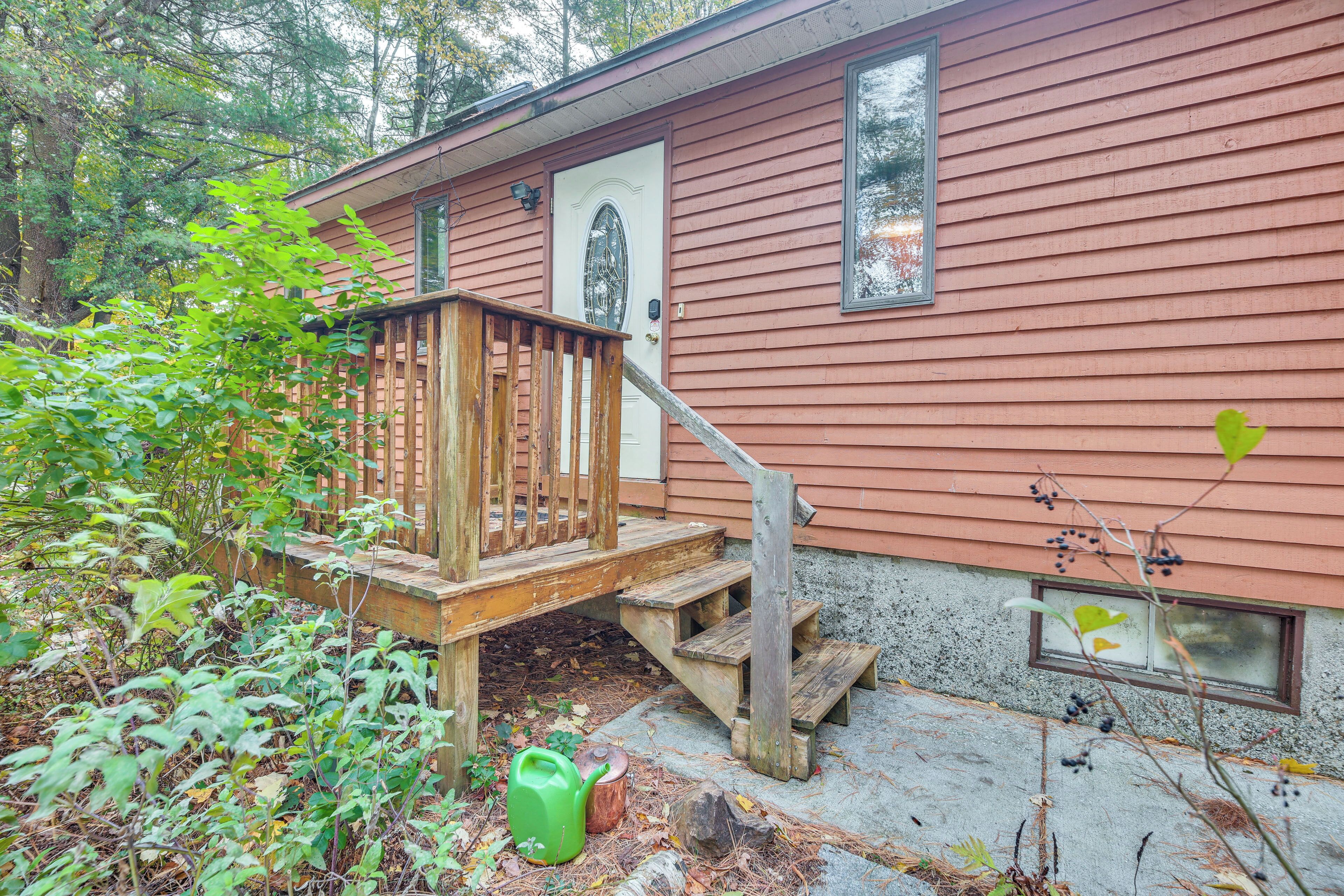 Une cabane en bois avec un escalier en bois menant à la porte d’entrée, entourée d’arbres et de végétation.