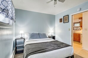 Un dormitorio con cama, lámparas de noche, ventilador de techo y vistas a la cocina.