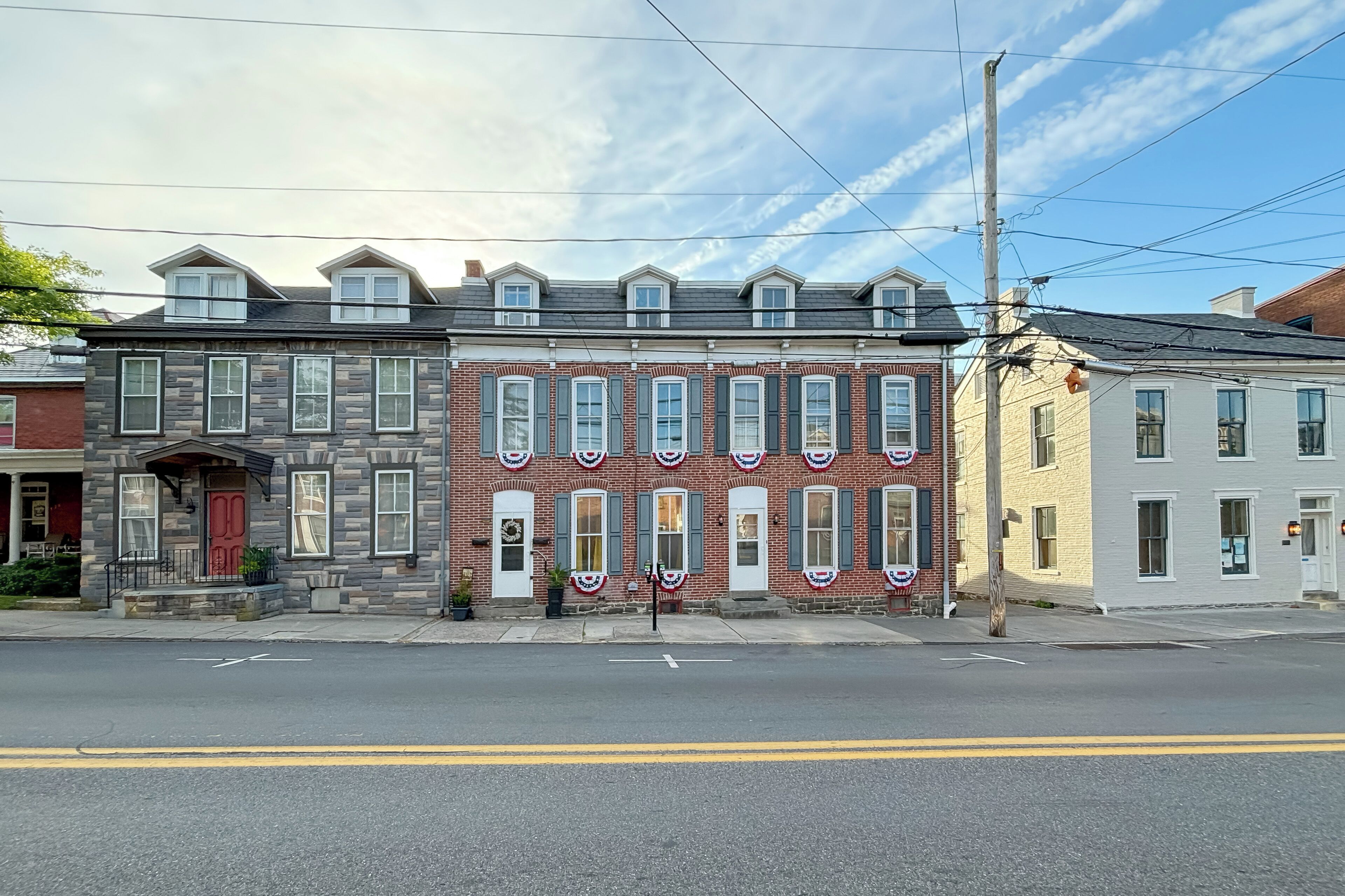 A row of townhouses with a red door, a brick facade, and a clear sky.