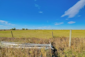 A rural landscape with a fence, a field, and a clear sky.