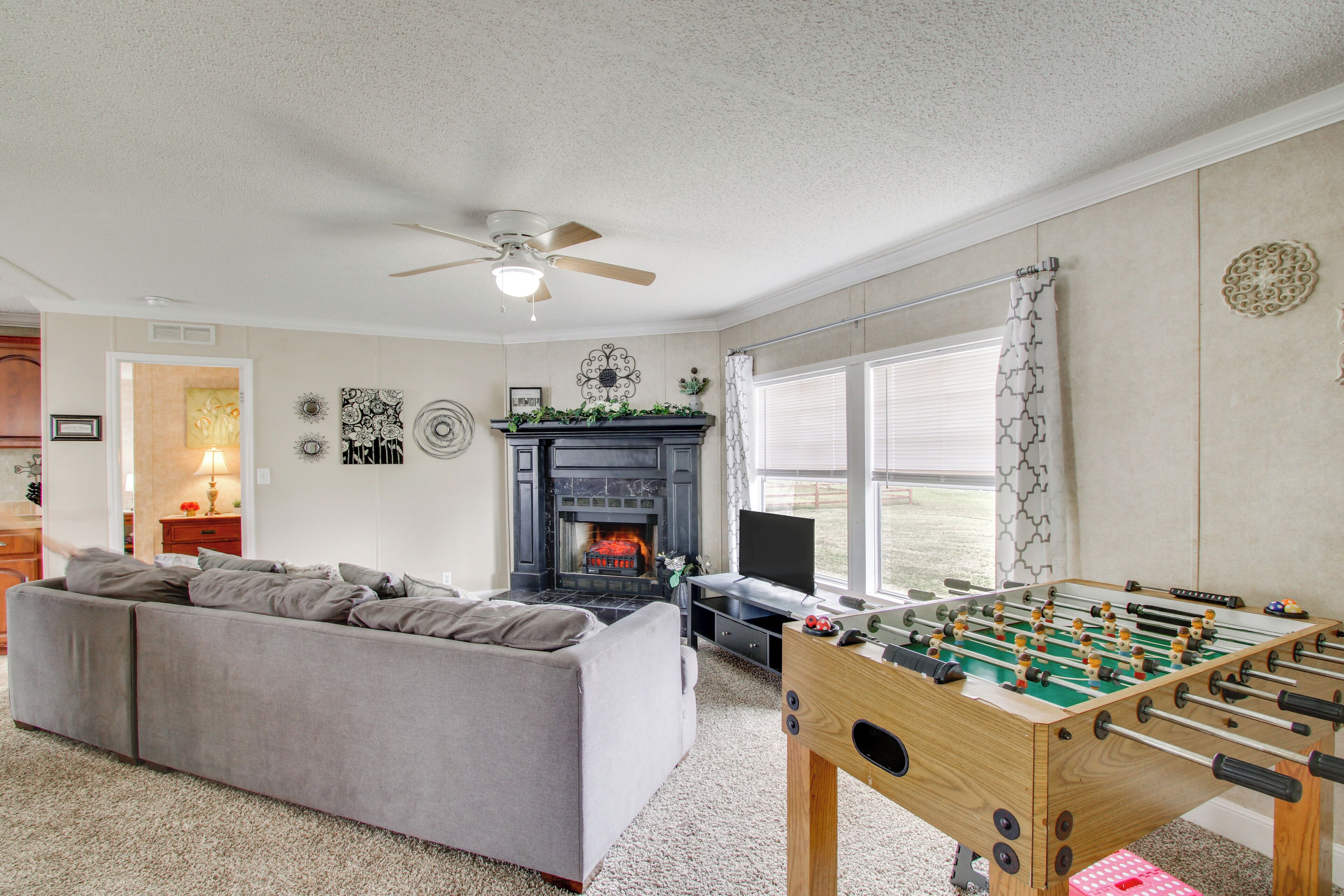 A living room with a sofa, a fireplace, a television, and a foosball table.