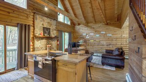 Ein Holzblockhaus-Interieur mit Küche, Essbereich und Kamin aus Stein.