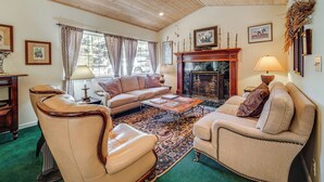 Ein gemütliches Wohnzimmer mit Kamin, Ledersesseln, einer Couch und einem Couchtisch.