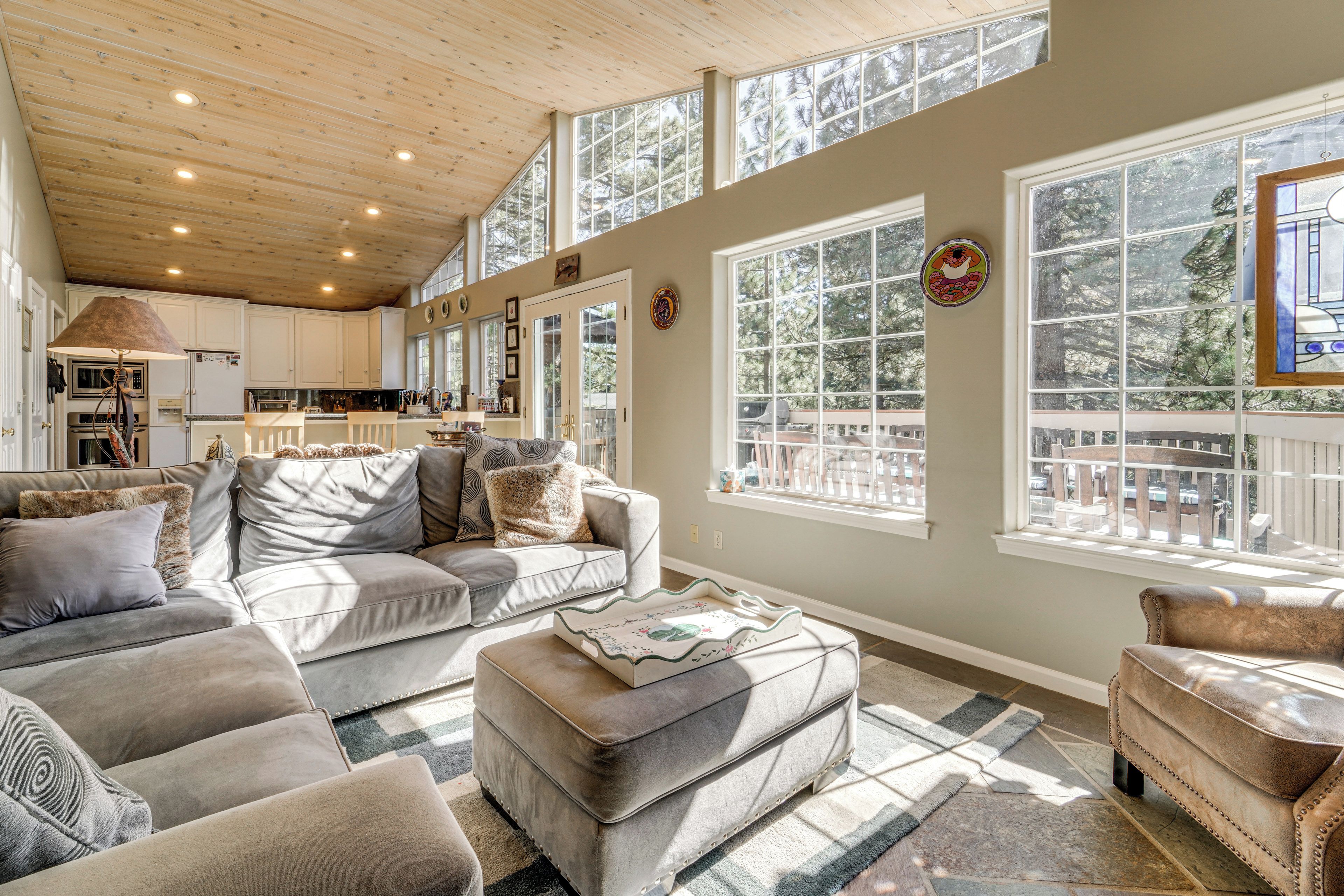 A spacious living area with a high ceiling, large windows, and a cozy seating arrangement.