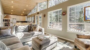 A spacious living area with a high ceiling, large windows, and a cozy seating arrangement.