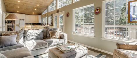 A spacious living area with a high ceiling, large windows, and a cozy seating arrangement.