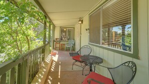 Une véranda abritée avec une table et des chaises, une fenêtre avec des stores et une vue sur l’extérieur.