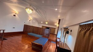 Una habitación amplia con piso de madera, un sofá, una mesa pequeña y una silla.