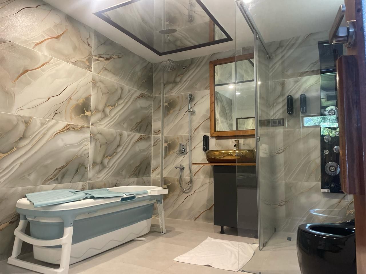 A modern bathroom with a freestanding bathtub, a glass-enclosed shower, and a marble-patterned wall.